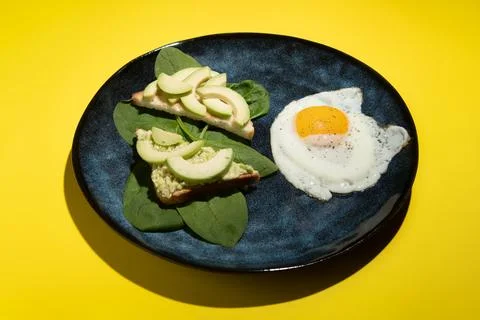 Breakfast dish of scrambled eggs and sandwiches with avocado and spinach on a Stock Photos