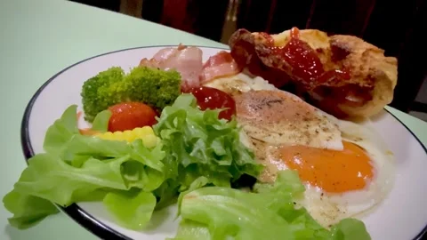 Breakfast dish.there are fried eggs,bread,some vegetable,bacon Video stock 334031012