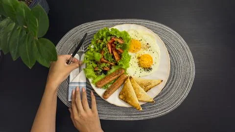 Breakfast eating process sequence from full plate with fried eggs, sausages.. Stock Photos