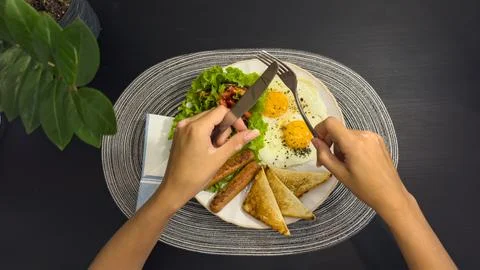 Breakfast eating process sequence from full plate with fried eggs, sausages.. Stock Photos