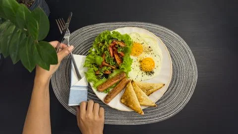 Breakfast eating process sequence from full plate with fried eggs, sausages.. Stock Photos