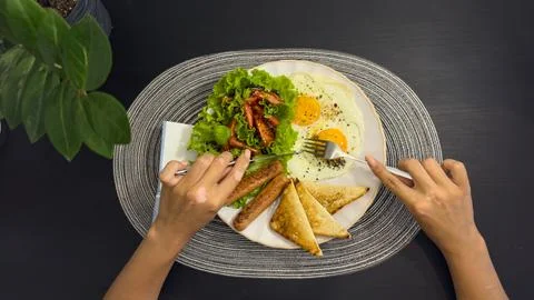 Breakfast eating process sequence from full plate with fried eggs, sausages.. Stock Photos