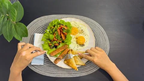 Breakfast eating process sequence from full plate with fried eggs, sausages.. Stock Photos