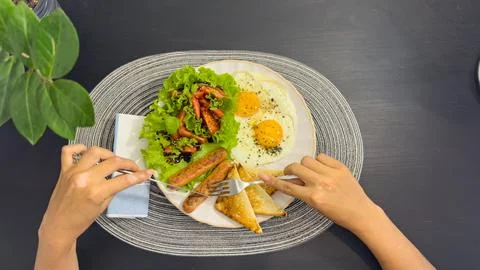 Breakfast eating process sequence from full plate with fried eggs, sausages.. Stock Photos