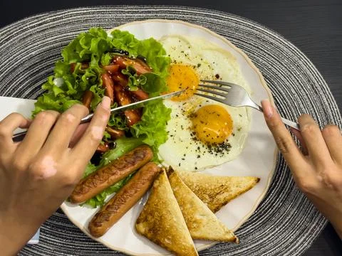 Breakfast eating process sequence from full plate with fried eggs, sausages.. Stock Photos