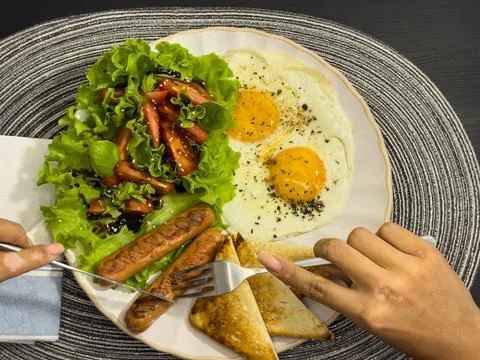 Breakfast eating process sequence from full plate with fried eggs, sausages.. Stock Photos