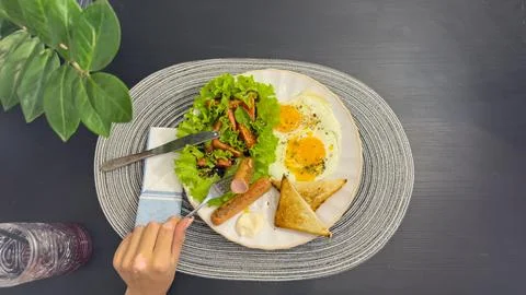 Breakfast eating process sequence from full plate with fried eggs, sausages.. Stock Photos