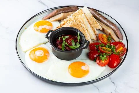 Breakfast of eggs and vegetables with cherry tomatoes and slices of bread side Stock Photos