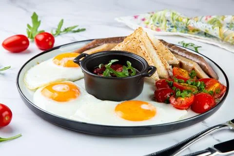 Breakfast of eggs and vegetables with cherry tomatoes and slices of bread side Foto stock