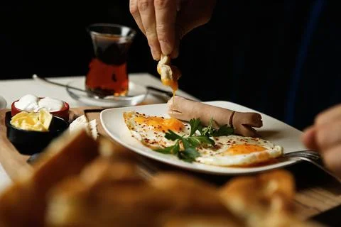 Breakfast with eggs, tea, and bread on a dining table in morning light Stock Photos