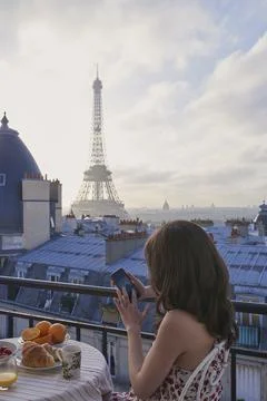 Breakfast, Eiffel Tower and phone with woman on balcony of hotel for holiday Stockfoto's