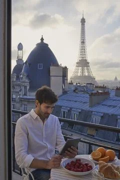 Breakfast, Eiffel Tower and tablet with man on balcony of hotel for holiday Stockfoto's
