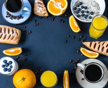 Breakfast flat lay with cup of coffee, oranges, buns, juice, oatmeal and yogurt Stock Photos