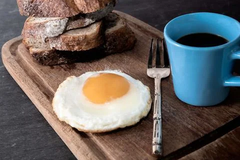 Breakfast food fried egg bread slice has espresso coffee in cutting board. Stock Photos