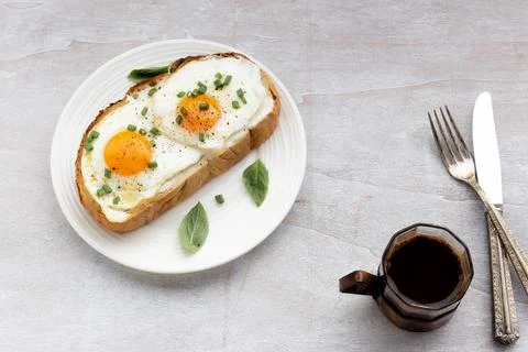 Breakfast food fried egg on bread slice in plate and coffee on white wood tab Stock Photos