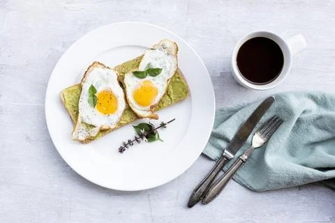Breakfast food fried egg on bread avocado spread and coffee on white wood t.. Stock Photos