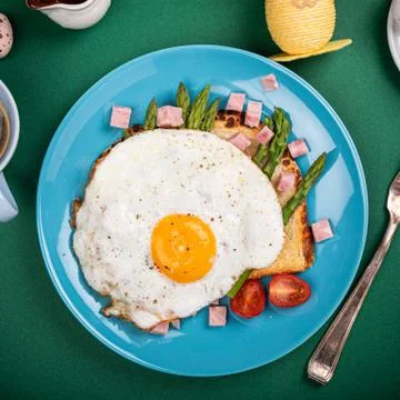 Breakfast with fried egg, bread toast, green asparagus, tomatoes and bacon Stock Photos