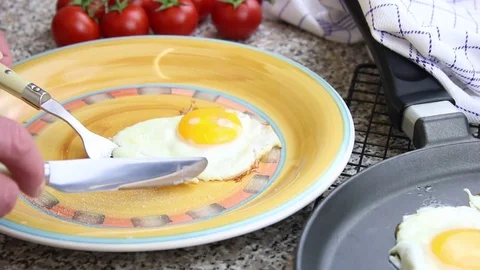 Breakfast with a fried egg on a plate, tomatoes in the background Stock Footage 74182605