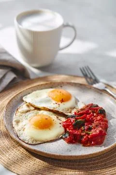 Breakfast with fried eggs and fried tomatoes with spinach on plate and cup of Stock Photos