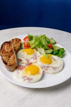 Breakfast of fried eggs with bacon, mixed salad and toasted bread Stock Photos