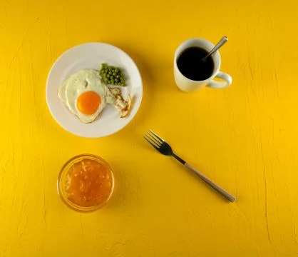 Breakfast: fried eggs, bread, coffee in a white cup on a yellow background. T 写真素材