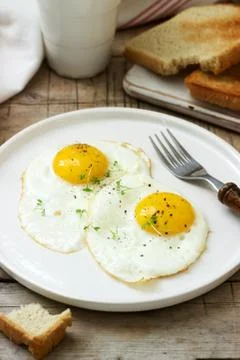 Breakfast of fried eggs, bread toasts and coffee on a wooden table. Rustic st Stock Photos