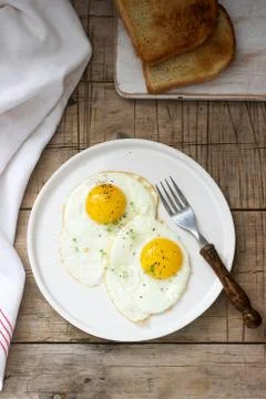 Breakfast of fried eggs, bread toasts and coffee on a wooden table. Rustic st 스톡 사진