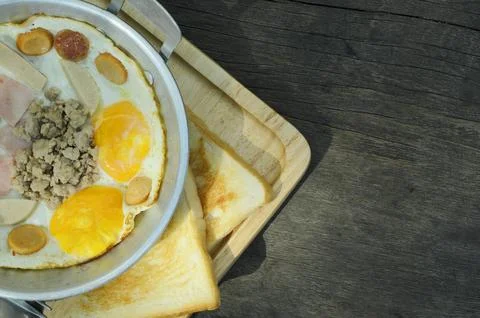 Breakfast with fried eggs in a pan with Sliced ??bread and bacon on wooden .. Stock Photos