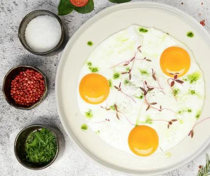 Breakfast. fried eggs from three eggs are sprinkled with grass on a light plate Stock Photos