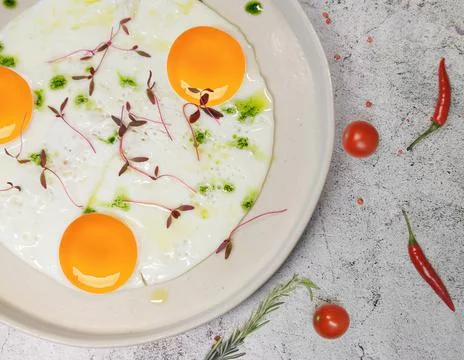 Breakfast. fried eggs from three eggs are sprinkled with grass on a light plate Stock Photos