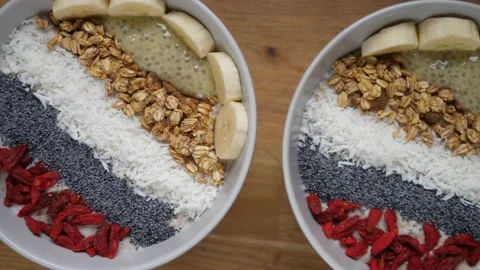 Breakfast on holidays. Top view of two smoothie bowls topped with banana, seeds Video stock 157411670