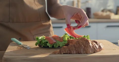 Breakfast at home. Female chef making croissant sandwich with lettuce and salmon Stock Footage 252037057