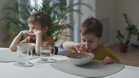 Breakfast in the home kitchen. Portrait of two little kids eating Stock Footage 164220468