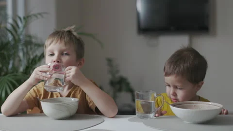 Breakfast in the home kitchen. Portrait of two little kids eating Stock Footage 164220616