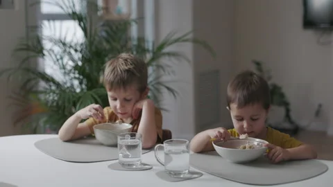 Breakfast in the home kitchen. Portrait of two little kids eating  Stock Footage 164220687