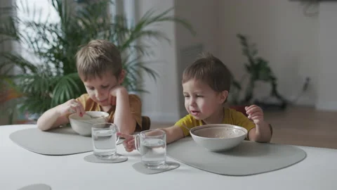 Breakfast in the home kitchen. Portrait of two little kids eating Stock Footage 164220941