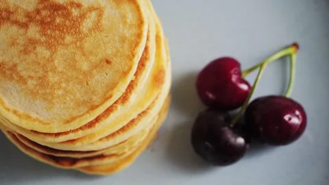 Breakfast with hot pancakes served with cherry. Pancakes sprinkled with fluffy Stock Footage 327384034
