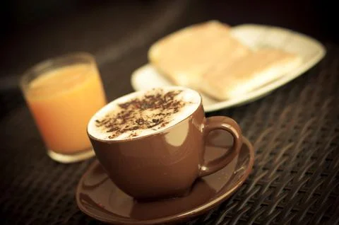 Breakfast including a cup of coffee, an orange juice and two toasts Stock Photos