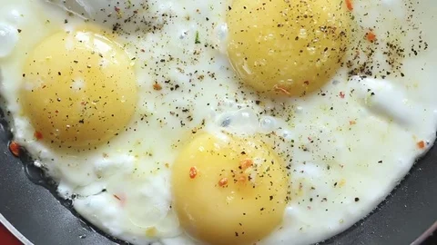 Breakfast just cooked with scrambled eggs in a frying pan sprinkle with spices Stock Footage 78499446