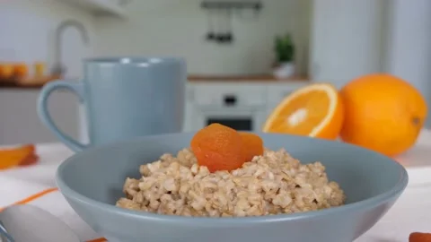 Breakfast in the kitchen, oatmeal with dried apricots and oranges. Stock Footage 154298188