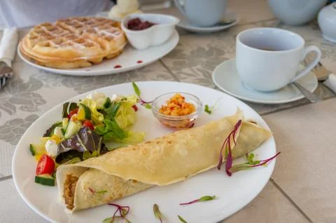 Breakfast, light meal table setting with crepe wrap, salad and Belgian waffle Stock Photos