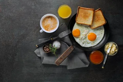 Breakfast made with fried eggs, jam, butter and beverage Stock Photos