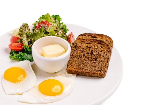 Breakfast meal with eggs, salad, bread, and butter on a white plate Stock Photos
