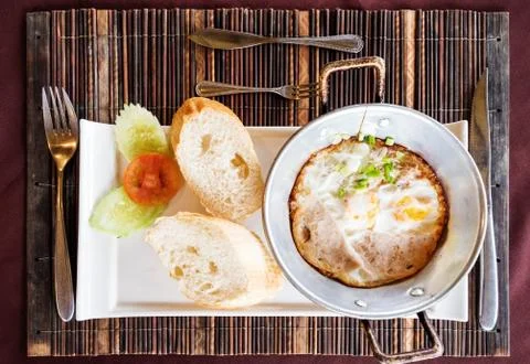 Breakfast meal, fried eggs pan and breads on the table Stock Photos