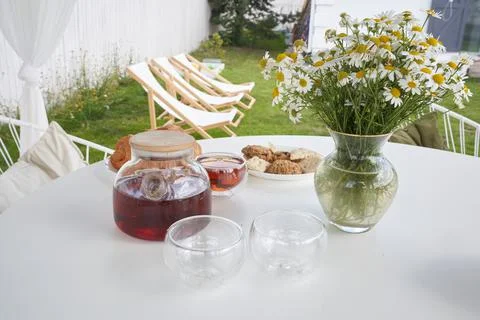 Breakfast in nature. Tea, cups, biscuits and croissants, chamomile flowers in a Stock-Fotos