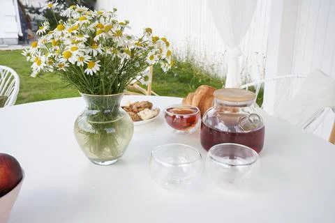 Breakfast in nature. Tea, cups, biscuits and croissants, chamomile flowers in a Stock Photos
