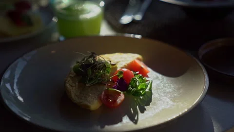 Breakfast omelet with vegetables stands on the table in the rays of the sun Stock Footage 273381620