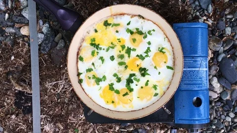 Breakfast omelette being cooked on a gas stove inside a tent Stock Footage 88939280