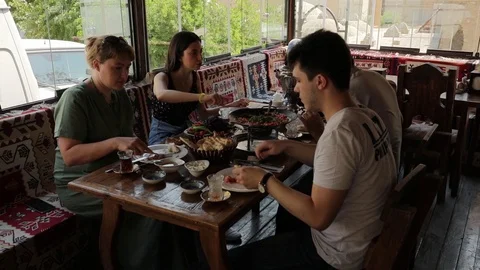 Breakfast in oriental cafe. On the table are samovar and snacks. Everyone eats Stock Footage 123543199