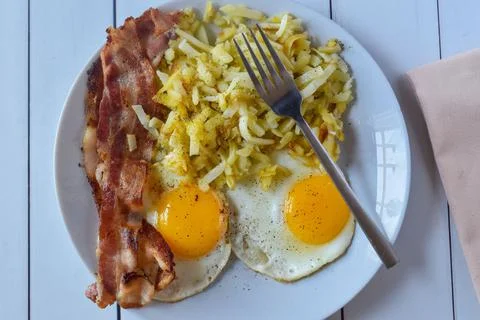 Breakfast plate of bacon eggs fried eggstop with pepper Stock Photos